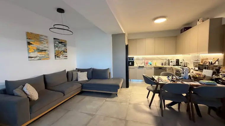 The renovated three-bedroom: the living room, with the sofa, the dining table and the kitchen